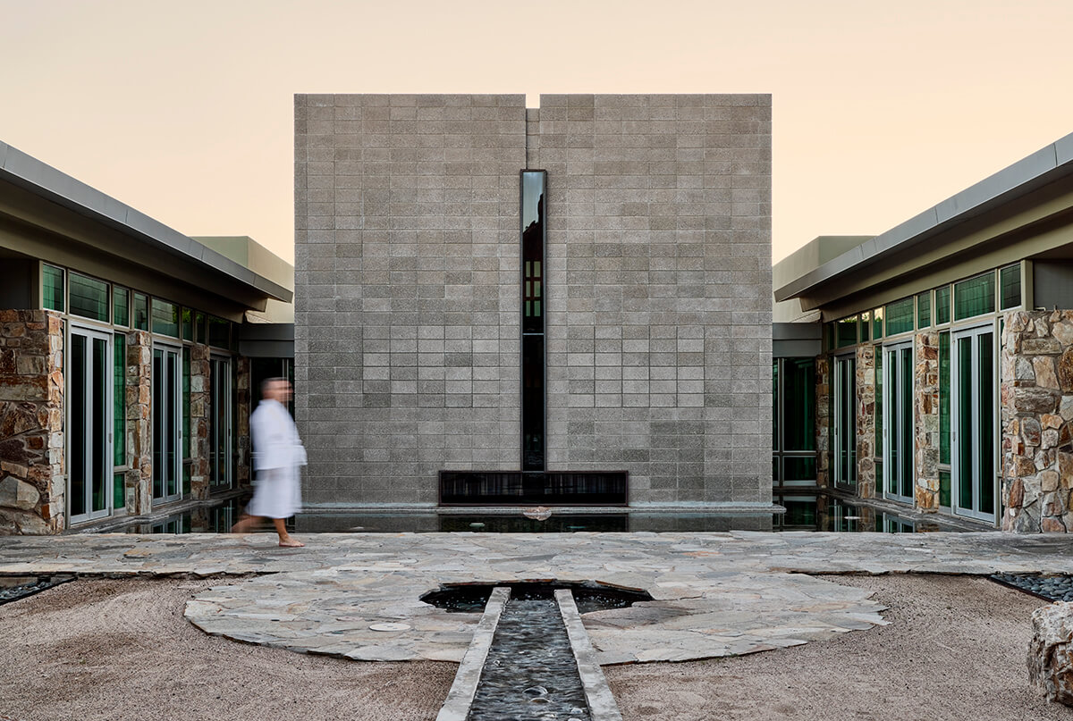 A beautiful outdoor spa and wellness center located in a desert landscape, with the majestic Camelback Mountain in the background. 