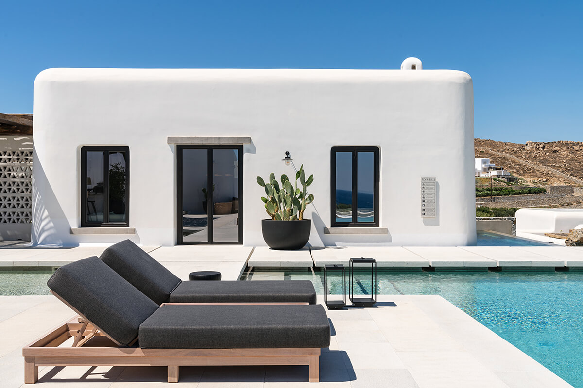 A beautiful  rectangular shaped pool and features sparkling blue water with lounge chairs and umbrellas positioned around it. 